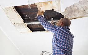 A man diligently working on a room's ceiling, focused and determined to complete the task at hand.